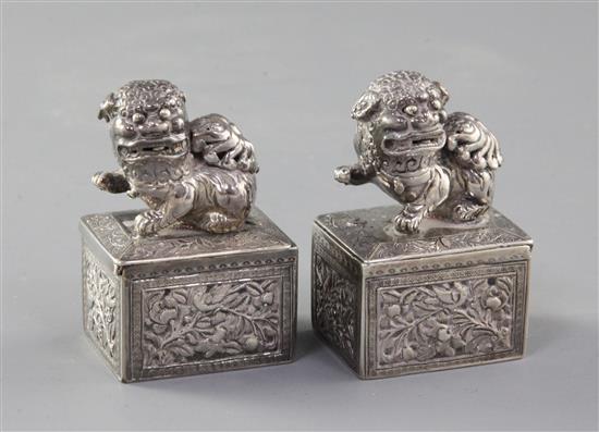 A pair of late 19th/early 20th century Chinese Export silver incense boxes, each with sliding lid surmounted with a Buddhist lion,